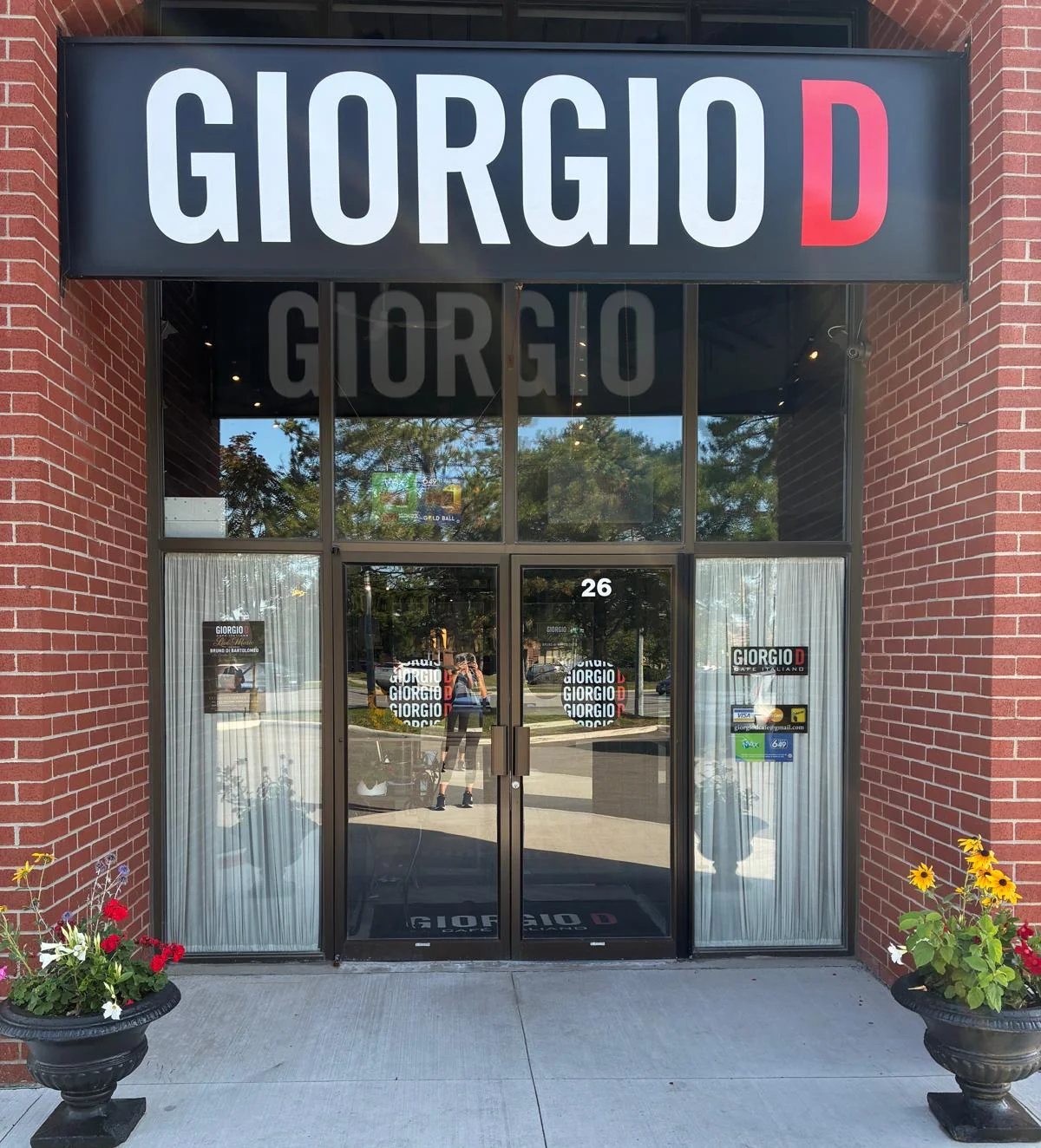 The Giorgio D storefront — red brick entrance and flower urns under the black and red sign